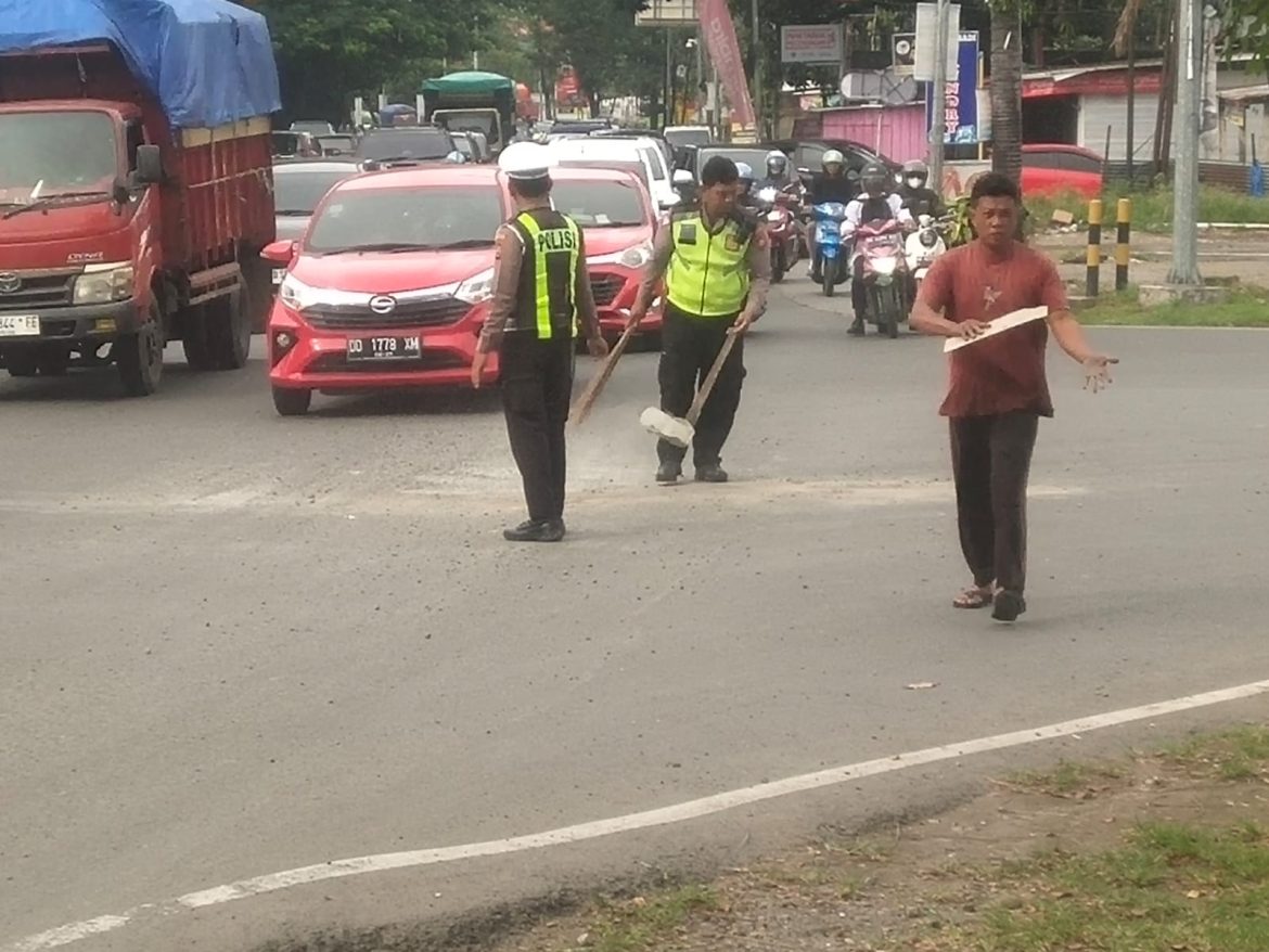 RESPON CEPAT PERSONIL LANTAS POLSEK BIRINGKANAYA BERSAMA WARGA BERSIHKAN TUMPAHAN MATERIAL BANGUNAN 